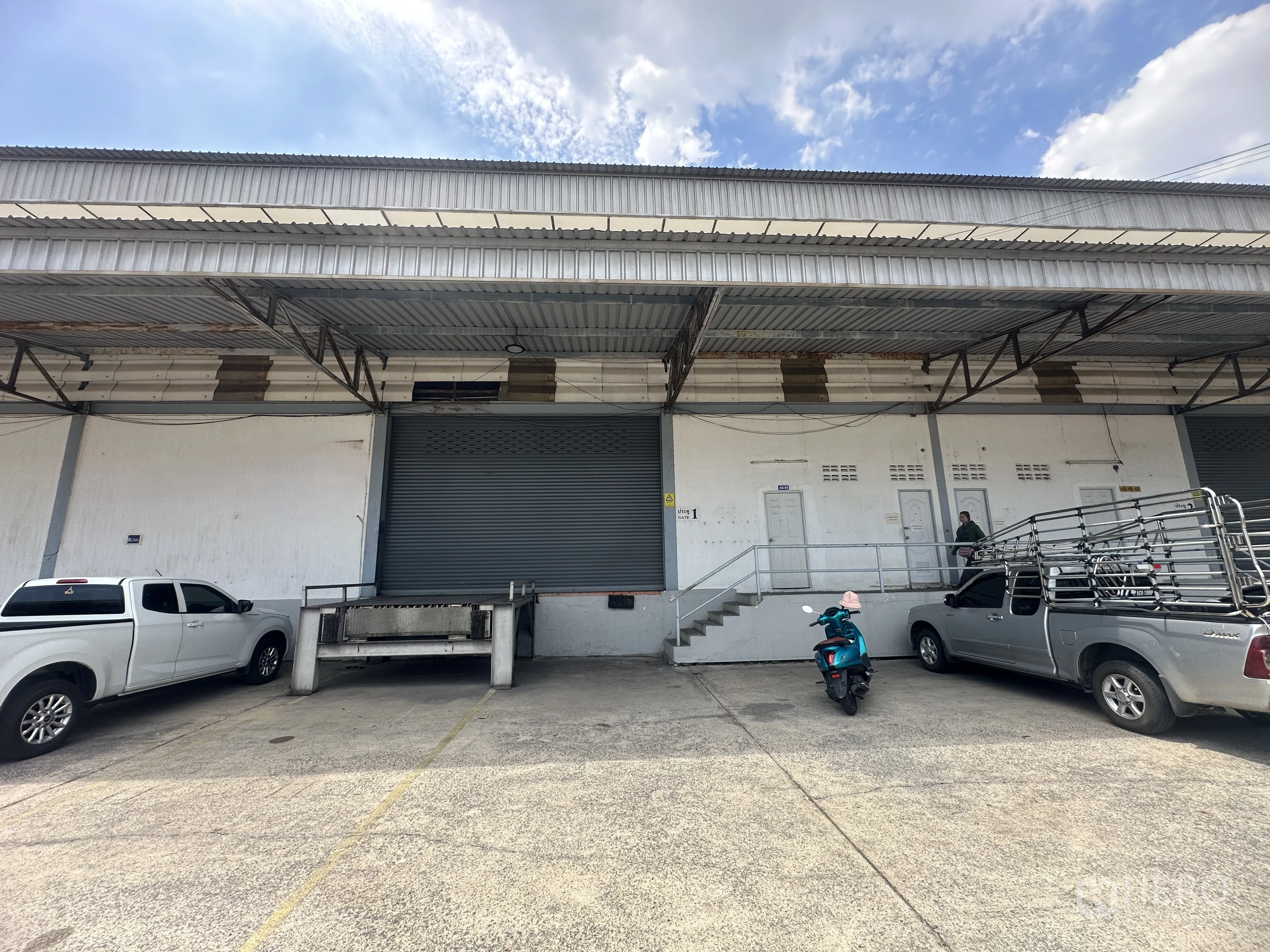 仓库 for rent in Khlong Luang, Pathum Thani - 多处月台装卸位，带楼梯与卷闸门，前方停有车辆。