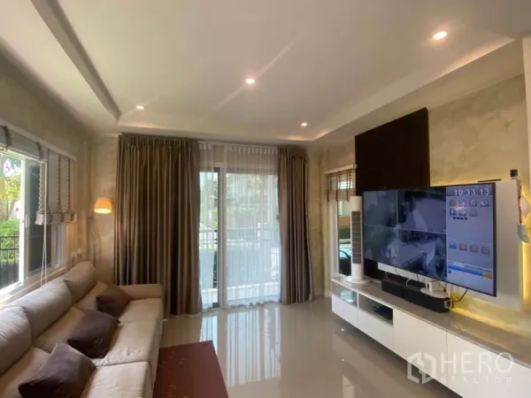 บ้าน ขายในBang Sao Thong, Samut Prakan - ห้องนั่งเล่นสว่างด้วยหน้าต่างบานใหญ่ ไฟดาวน์ไลท์ และชั้นวางทีวี