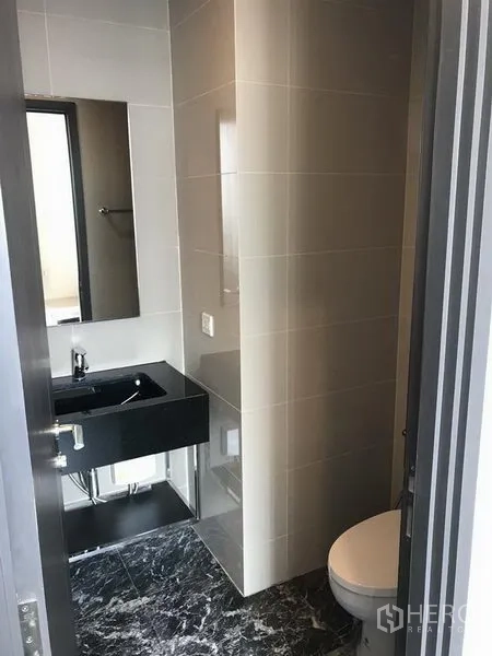 คอนโด ให้เช่าในWatthana, Bangkok - ห้องน้ำร่วมสมัยพร้อมอ่างล้างหน้าสีดำ กระจก และโถสุขภัณฑ์ พื้นลายหินอ่อน