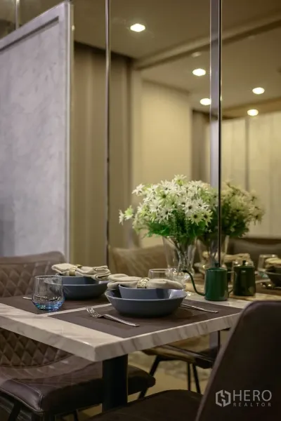 คอนโด ให้เช่าในWatthana, Bangkok - โต๊ะทานอาหารหินอ่อนจัดสำหรับสอง พร้อมแจกันดอกไม้และผนังกระจก