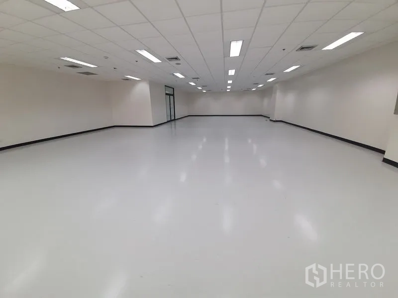 办公空间 出租在Bang Rak, Bangkok - 对称视角的明亮空置办公室，网格吊顶灯照明。