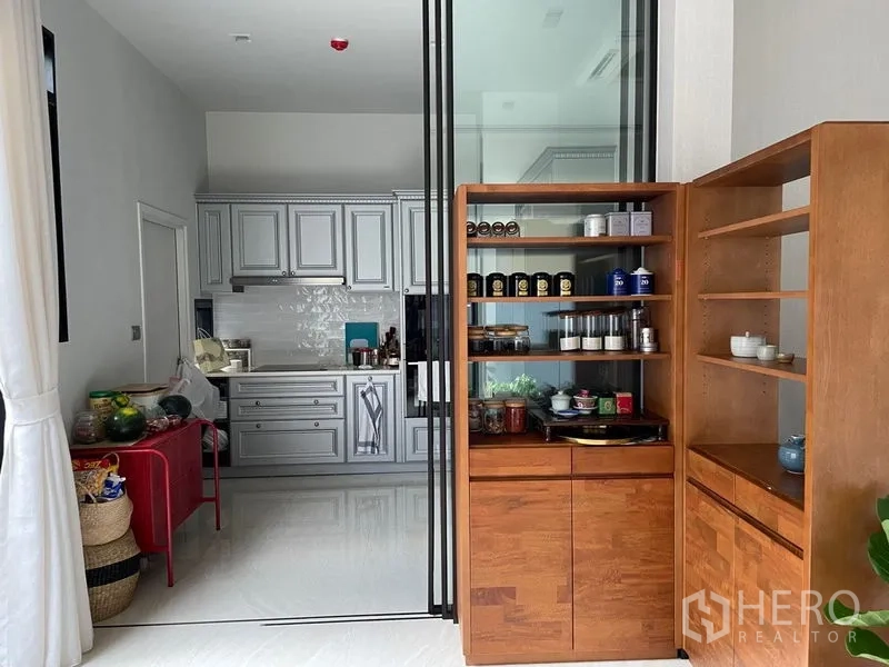 联排别墅 出售在Lat Phrao, Bangkok - 独立厨房在玻璃推拉门后，经典橱柜和木质储物架。