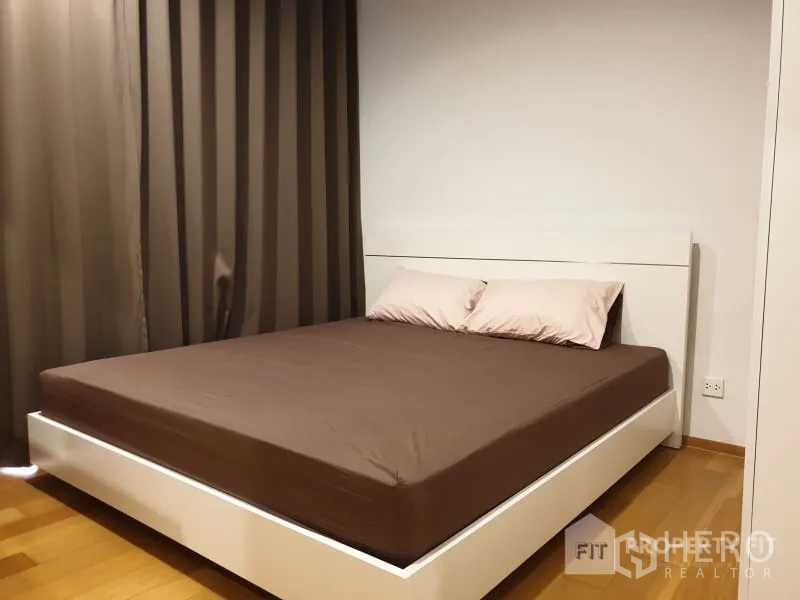 公寓 出租或出售在Bang Rak, Bangkok - 极简卧室，双人床、木地板与全遮光窗帘。