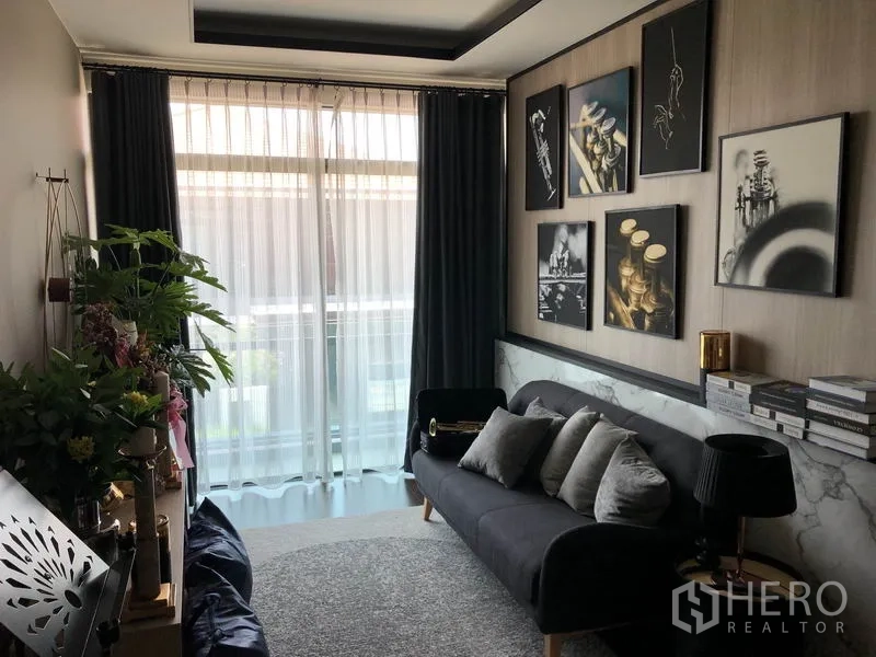 Detached House for rent in Bang Kapi, Bangkok - Upper-floor lounge or study with sofa, artwork gallery wall and sheer curtains.