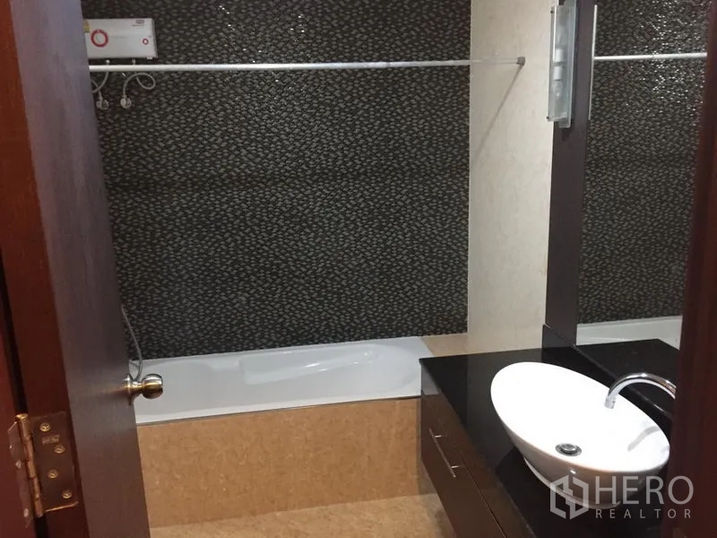 公寓 出租在Khlong Toei, Bangkok - 浴室设台上盆与黑色台面，墙面花纹瓷砖与浴缸