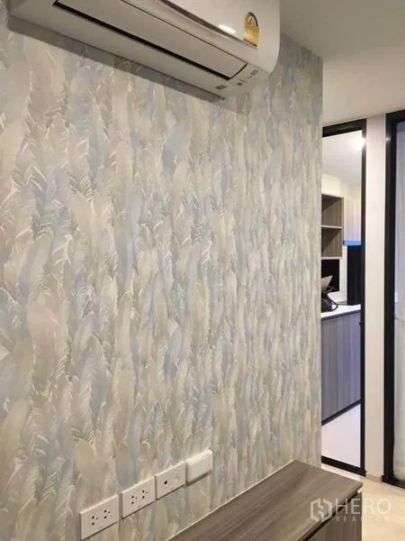 คอนโด ขายในBang Na, Bangkok - ผนังลวดลายโทนฟ้า มีปลั๊กไฟและเครื่องปรับอากาศ ใกล้ทางเข้าห้องครัว