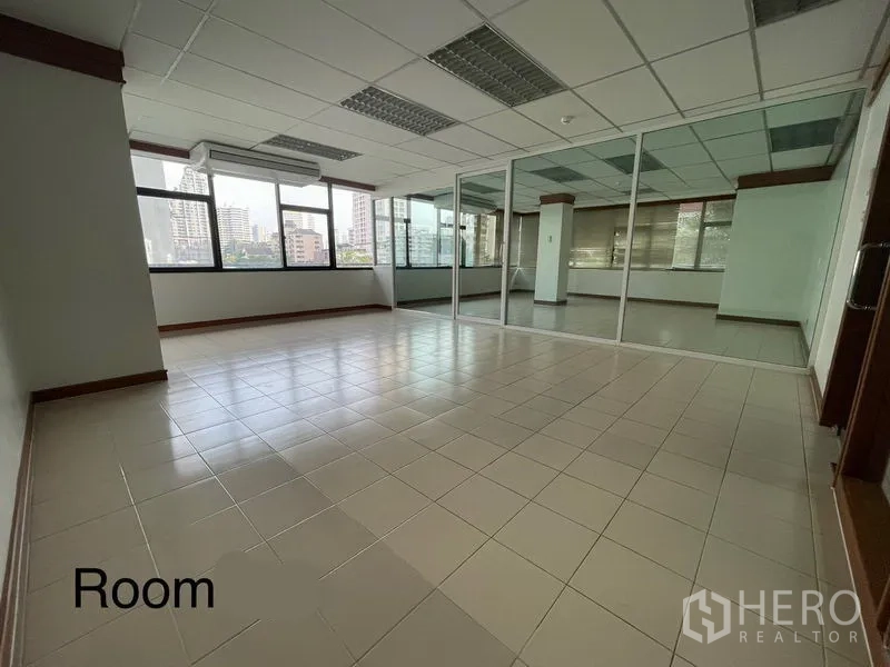 Office Space for rent in Khlong Toei, Bangkok - Bright 72 sqm office with tiled floors, large windows, and a glass-partitioned room with city views.