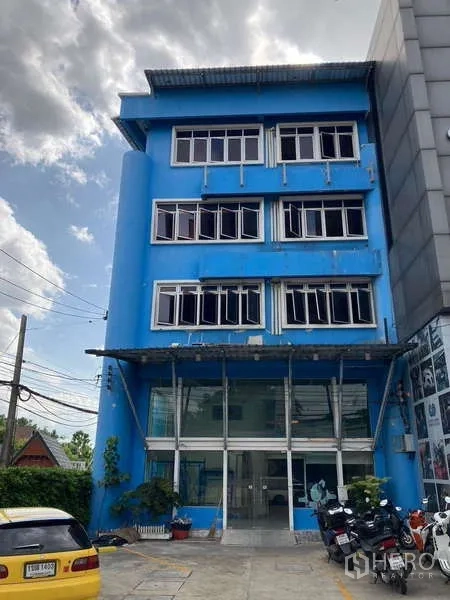 Shophouse for rent in Prawet, Bangkok - Four-storey blue shophouse exterior with glass-front entrance and parking in Prawet.