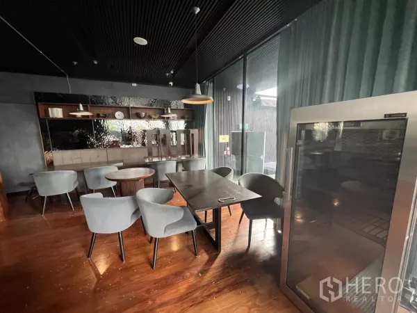 Retail Space for rent - Corner seating by tall glass doors and a display fridge under pendant lights.