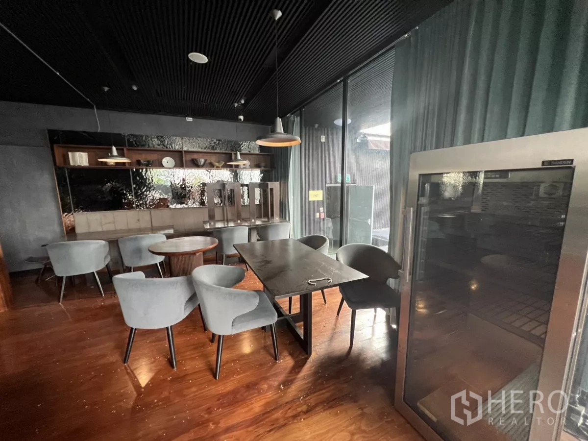 Retail Space for rent - Corner seating by tall glass doors and a display fridge under pendant lights.