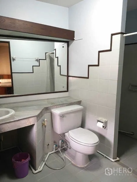 Townhouse for rent or sale in Suan Luang, Bangkok - Bathroom with vanity, large mirror and toilet beside a walk-in shower.