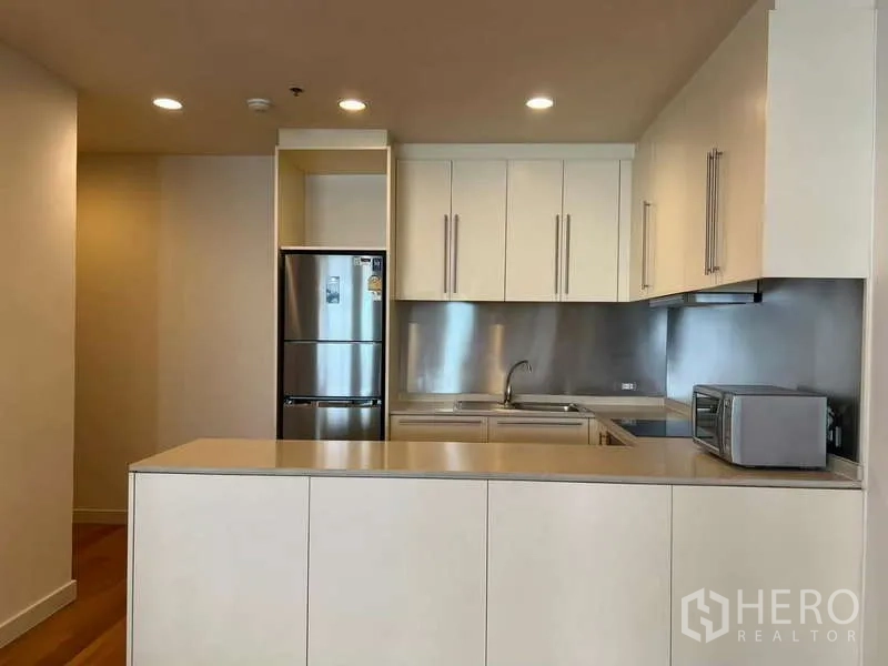 Condominium for rent in Bang Kho Laem, Bangkok - Open kitchen with breakfast counter, ample cabinets, and fridge.