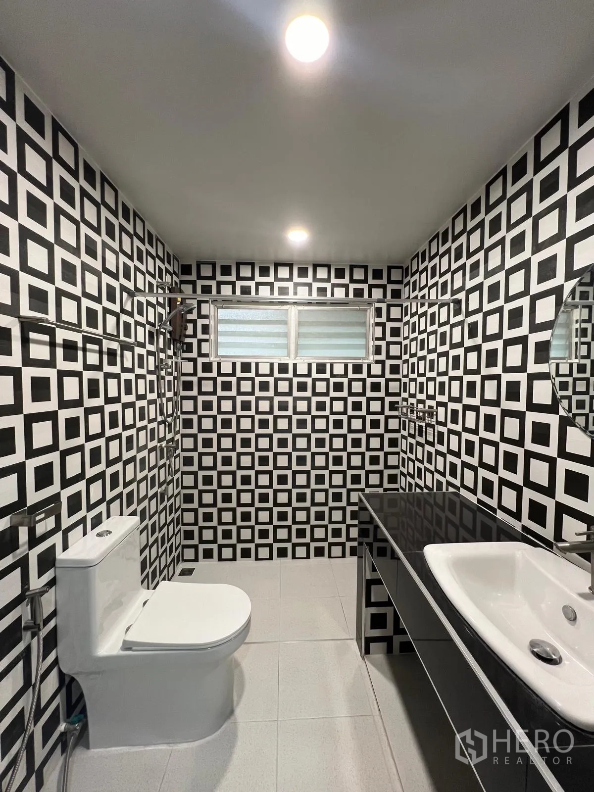 Detached House for rent in Saphan Sung, Bangkok - Contemporary bathroom with black-and-white geometric tiles, toilet, vanity and a frosted window.