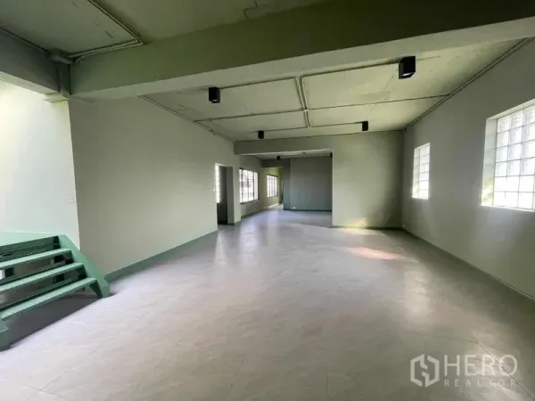 Home Office for rent in Phaya Thai, Bangkok - Spacious open-plan office floor with light green walls, ceiling lights, and side windows.