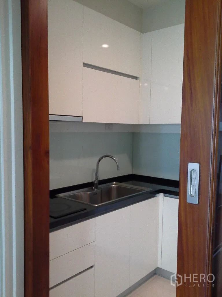 公寓 出租或出售在Khlong Toei, Bangkok - 紧凑L形厨房，配不锈钢水槽和木质推拉门。