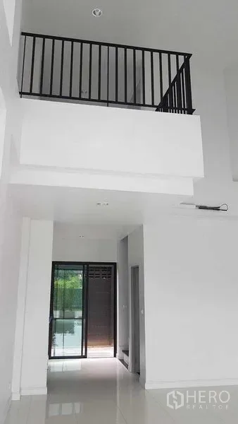 店屋 出租或出售在Bang Na, Bangkok - 挑高客厅，白色墙面、亮面地砖与黑色栏杆夹层。