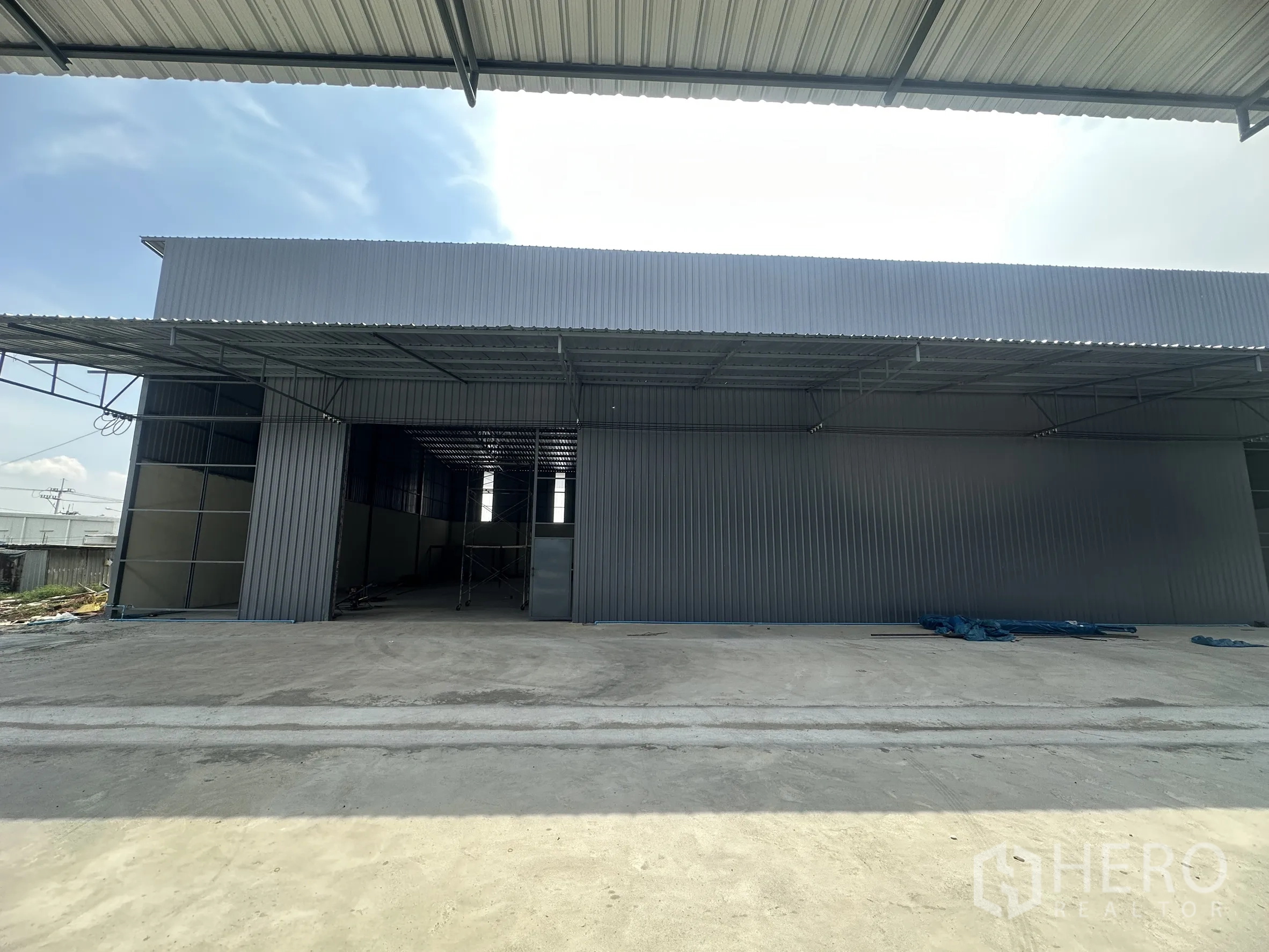 Warehouse for rent in Lam Luk Ka, Pathum Thani - Front of a warehouse unit featuring a wide entrance and canopy for loading.