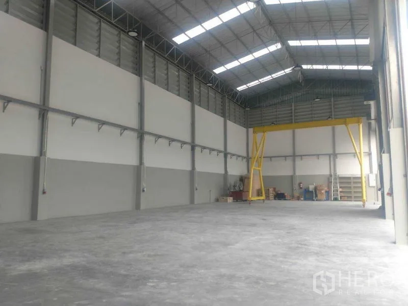 Warehouse for rent in Saphan Sung, Bangkok - Spacious clear-span floor with a material-handling gantry at the far end.