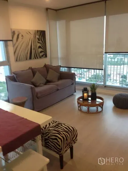Condominium for rent in Sathon, Bangkok - Bright living room at Rhythm Sathorn condo with sofa, balcony and city view through floor-to-ceiling windows.