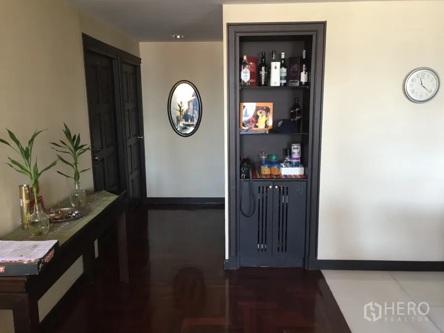 Condominium for rent or sale in Khlong Toei, Bangkok - Entry hallway of Khlong Toei Bangkok condo with dark parquet floor, console table and built-in shelving.