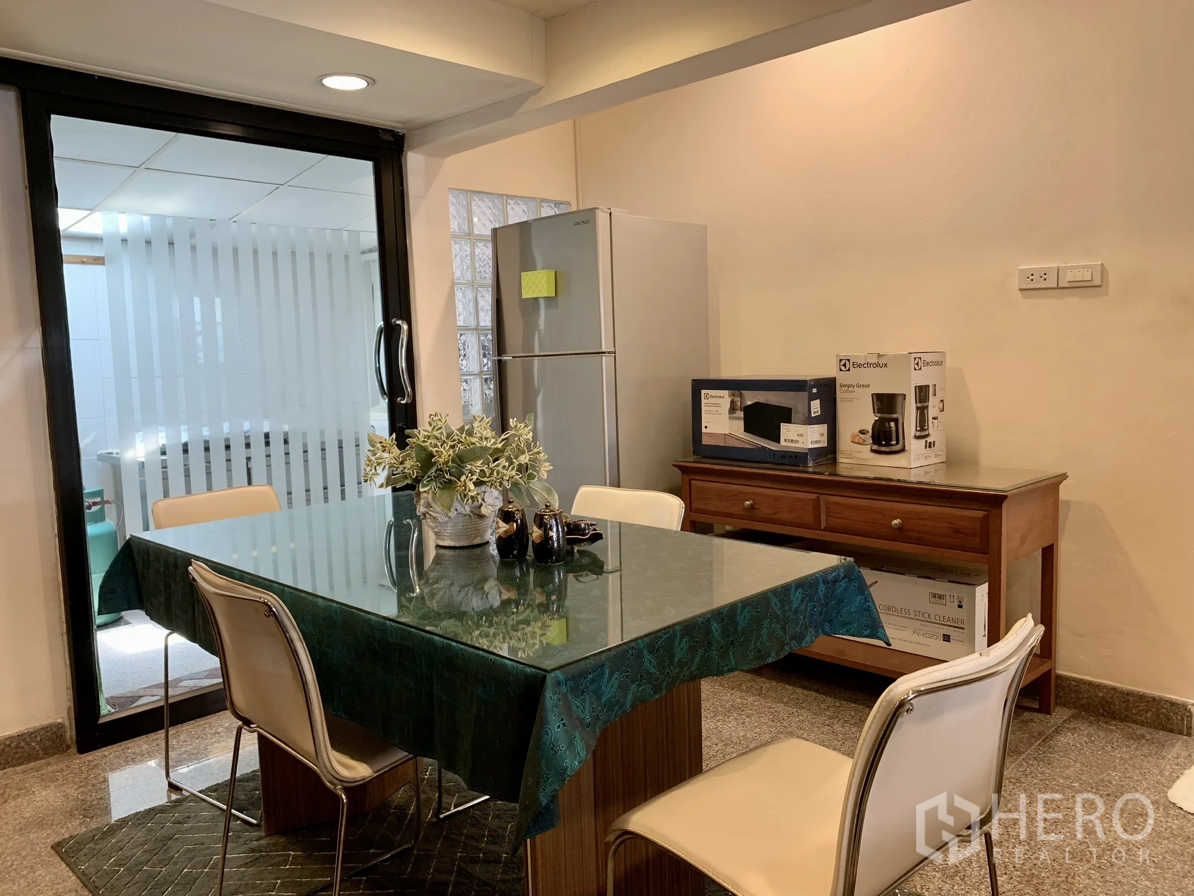 บ้านเดี่ยว for rent in Saphan Sung, Bangkok - พื้นที่รับประทานอาหารมีโต๊ะกระจก เก้าอี้สี่ตัว ตู้เย็น และตู้ลิ้นชักไม้.