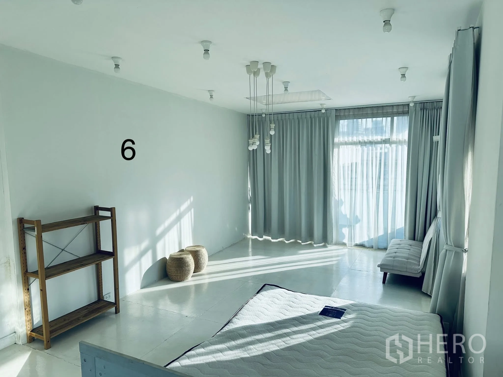 店屋 for rent in Watthana, Bangkok - 明亮的楼层房间，落地窗配纱帘，吊灯泡、木架和床垫。