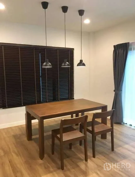 บ้าน ให้เช่าในBang Kapi, Bangkok - มุมรับประทานอาหาร โต๊ะไม้ โคมไฟแขวน 3 ดวง และบานเกล็ดสีเข้ม