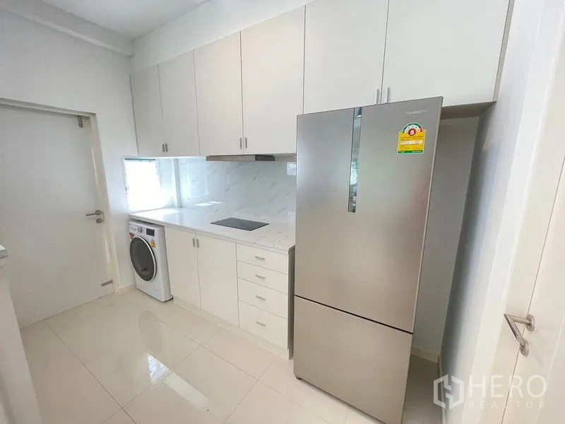 联排别墅 出租在Prawet, Bangkok - 现代白色厨房，充足橱柜、感应炉、大冰箱和洗衣机。