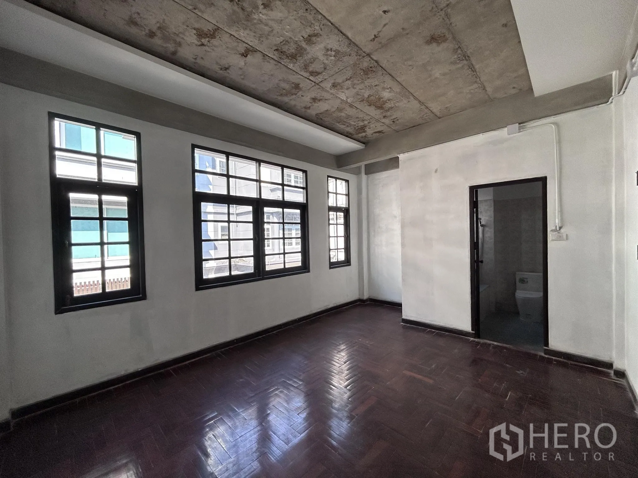 家庭办公室 for rent or sale in Watthana, Bangkok - 大房间配多扇窗、拼花木地与浴室入口。