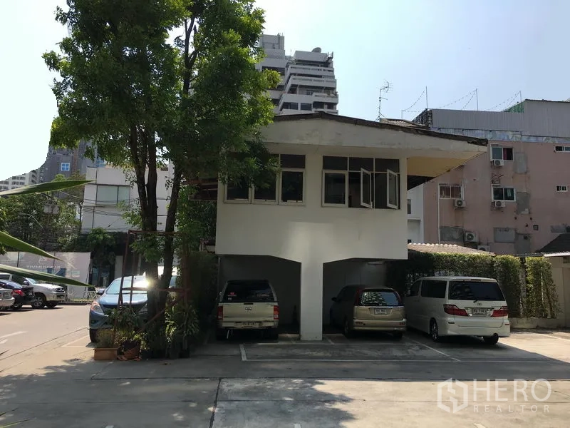 พื้นที่ขายปลีก ให้เช่าในWatthana, Bangkok - มุมหน้าอาคารเตี้ยสองชั้น มีที่จอดรถใต้ถุนและลานจอดหลายคัน ท่ามกลางอาคารเมือง