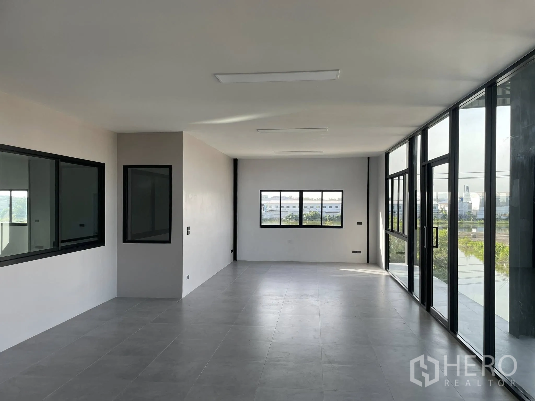 Warehouse for rent in Phra Samut Chedi, Samut Prakan - Bright office room with large windows and gray tile flooring.