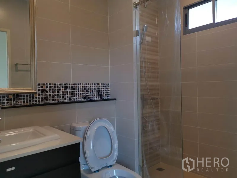 Detached House for sale in Nonthaburi - Second bathroom featuring a walk-in glass shower, mosaic backsplash and WC.