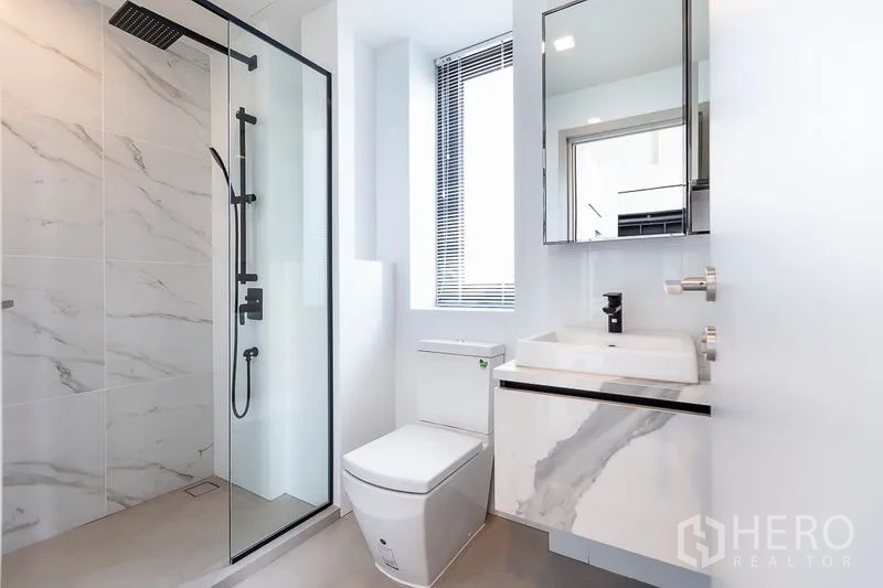 Condominium for rent in Phra Khanong, Bangkok - Modern bathroom with glass shower, rain head and marble-style vanity.