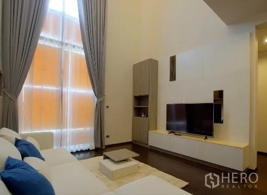 公寓 出租在Watthana, Bangkok - 客厅电视墙与地毯，配双层高度的落地窗帘。