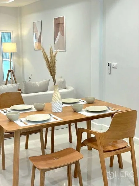 联排别墅 出售在Khlong Toei, Bangkok - 木质餐桌四人位，餐具摆放整齐，邻近客厅。