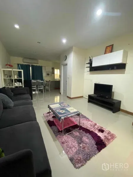Townhouse for rent in Suan Luang, Bangkok - Open-plan living room with sofa, TV console and polished tile flooring.