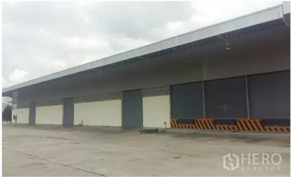 货栈 出租在Chon Buri - 仓库外观，带雨棚装卸平台与多扇卷闸门，卡车出入便捷