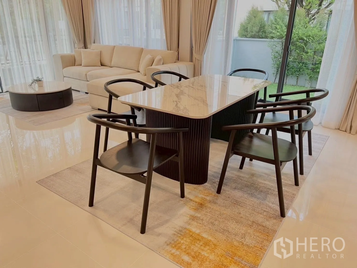 Detached House for rent in Bang Phli, Samut Prakan - Dining area with marble-top table and black chairs next to a beige sofa and garden view.