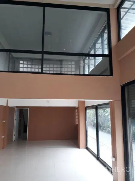 Townhouse for sale in Bang Kapi, Bangkok - Double-height living area with mezzanine and large sliding glass doors bringing in natural light.