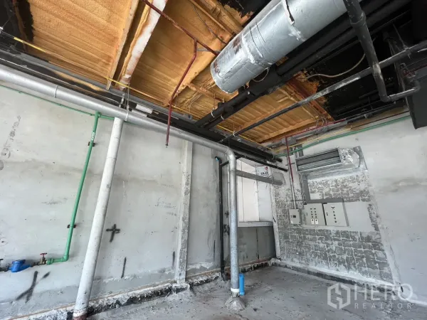 零售空间 出租在Pathum Wan, Bangkok - 服务墙特写，可见给排水管线、电控面板与保温天花。