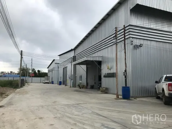 货栈 出租在Bang Phli, Samut Prakan - 金属板外墙仓库外观，卷闸门与宽阔混凝土车道，位于邦普里工业区。