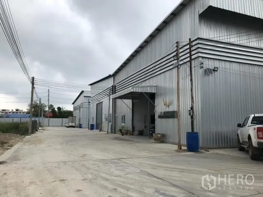 货栈 出租在Bang Phli, Samut Prakan - 金属板外墙仓库外观，卷闸门与宽阔混凝土车道，位于邦普里工业区。