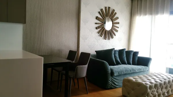 คอนโด ให้เช่าหรือขายในWatthana, Bangkok - ห้องนั่งเล่นสว่างด้วยโซฟาสีเขียว โต๊ะทานข้าว และหน้าต่างกระจกสูงในคอนโดย่านสุขุมวิท