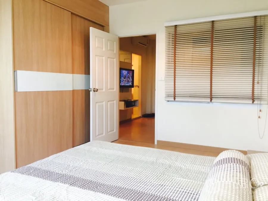 Condominium for rent in Watthana, Bangkok - Bright bedroom with sliding wood wardrobe, window blinds, and a view toward the living area with TV.