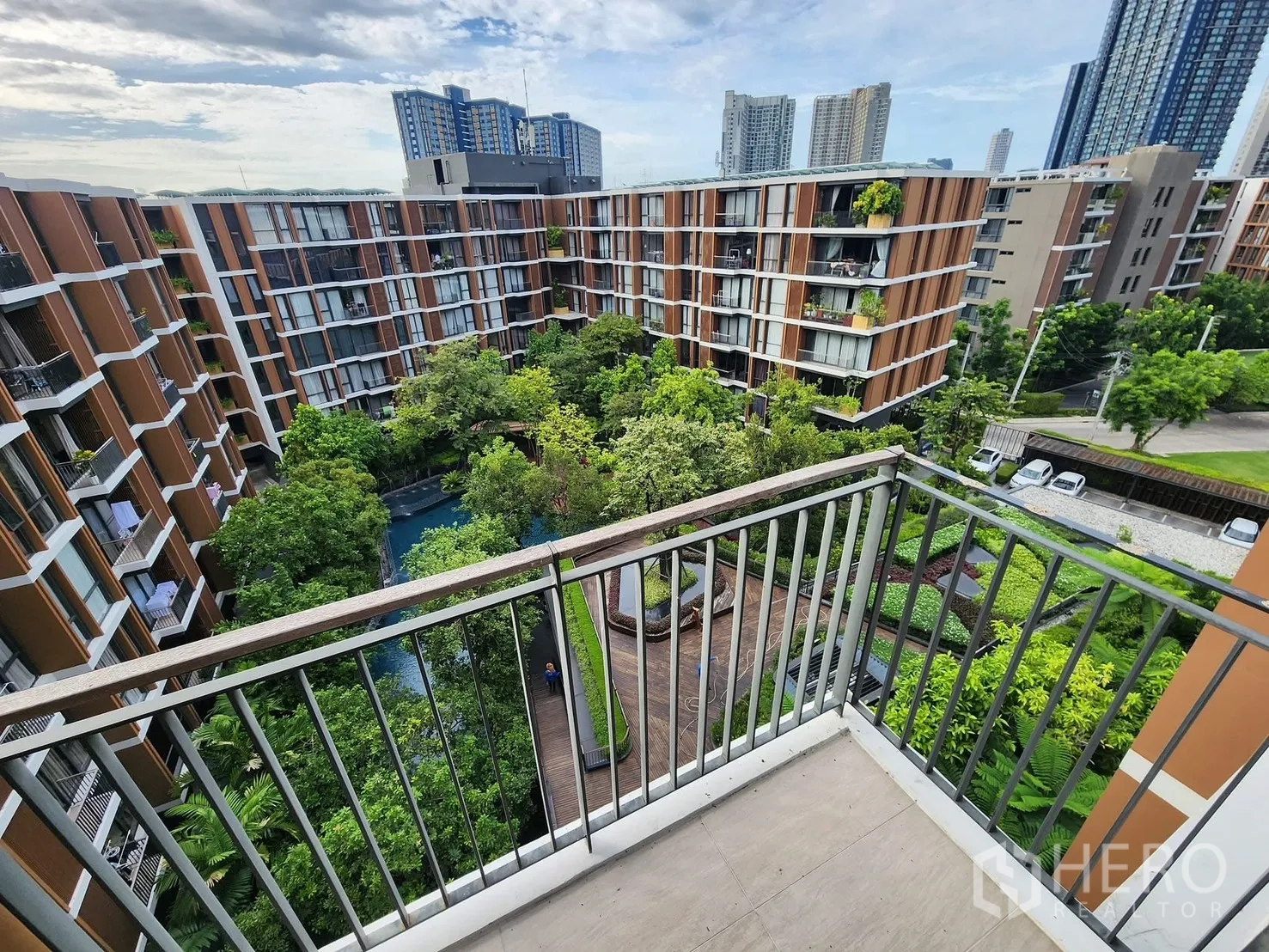 Condominium for rent in Watthana, Bangkok - Balcony view over a lush landscaped courtyard and low-rise condo buildings with city skyline beyond.