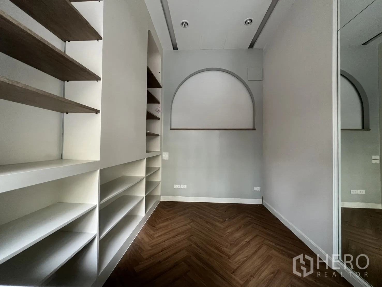 零售空间 for rent in Watthana, Bangkok - 紧凑房间带内置展示搁架，鱼骨拼木地板与拱形壁龛。