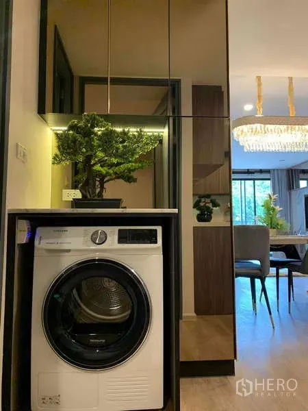 Condominium for rent - Compact laundry nook with front-load washer, mirrored storage and a view to the dining area with chandelier.