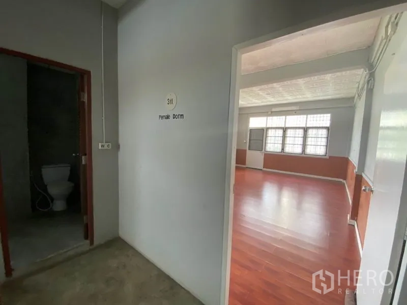 Retail Space for rent in Khlong San, Bangkok - Corridor with WC and signage leading to large room with timber flooring.