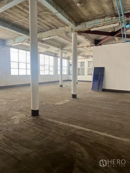 Shophouse for rent in Samphanthawong, Bangkok - Upper floor with white columns, rough wooden floor and exposed beams.