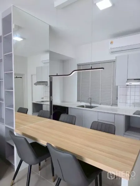 Townhouse for rent in Bang Phli, Samut Prakan - Long wooden dining table with four chairs beside mirrored wall and open kitchen.